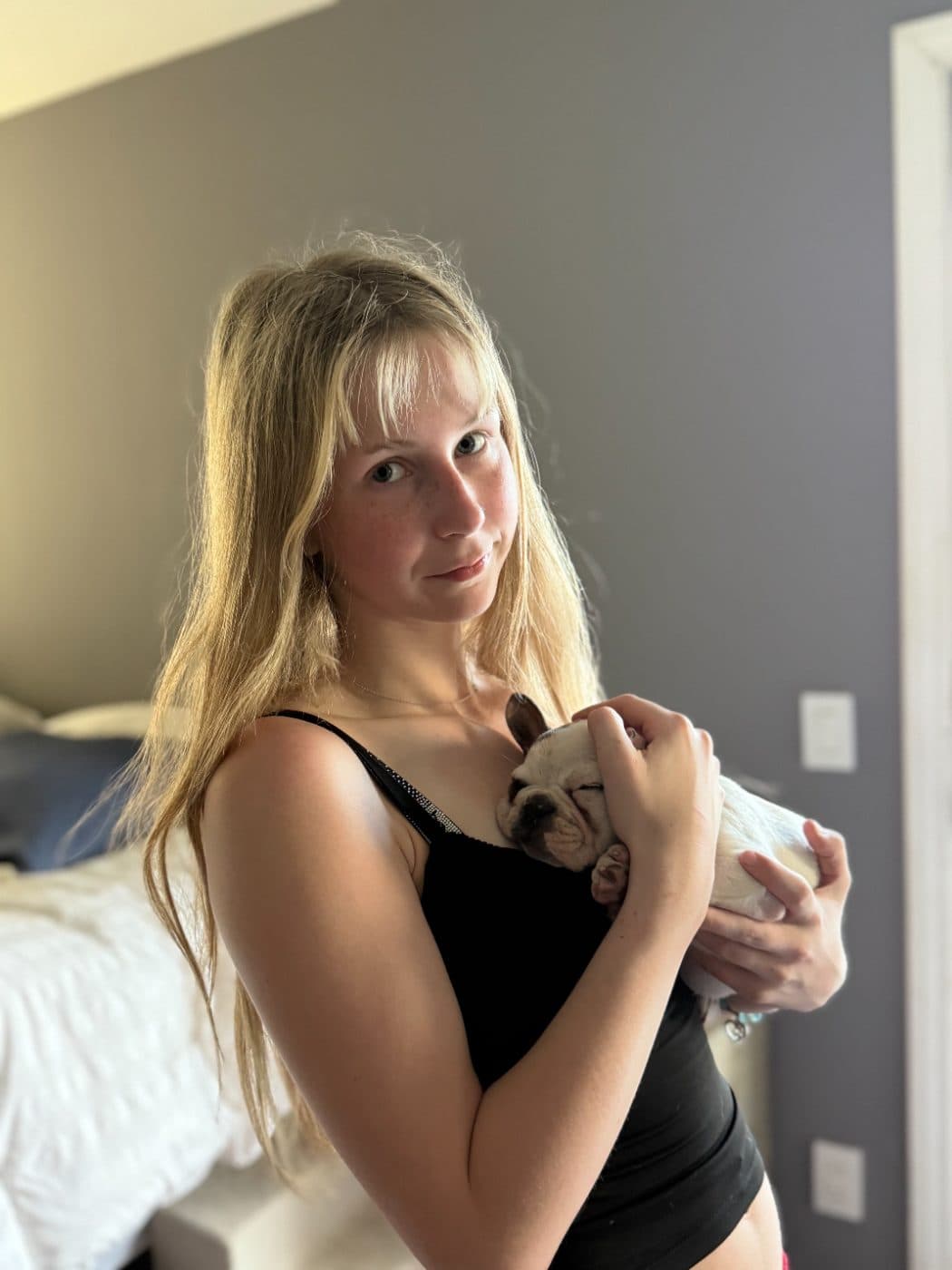 Brianna cradling a sleepy French bulldog puppy against her shoulder during a drop in visit in Thousand Oaks